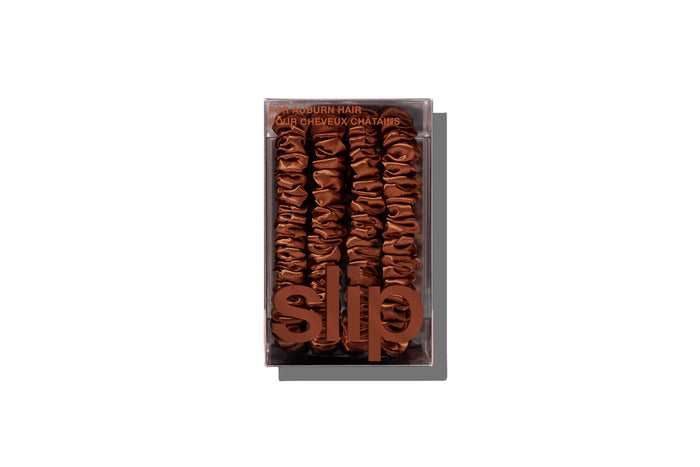 A set of four slip silk auburn skinny scrunchies in branded packaging on a white background.
