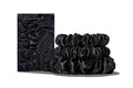 A set of three black colored slipsilk scrunchies, including two midi and one large, stacked in front of branded packaging on a white background.