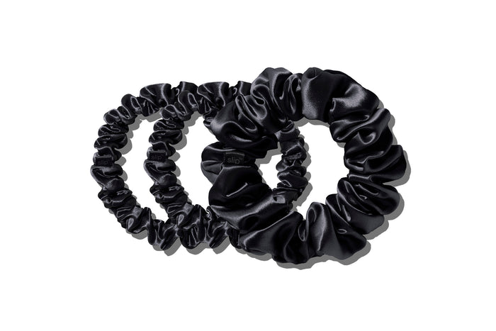 A set of three black slipsilk scrunchies, including two midi and one large, on a white background.