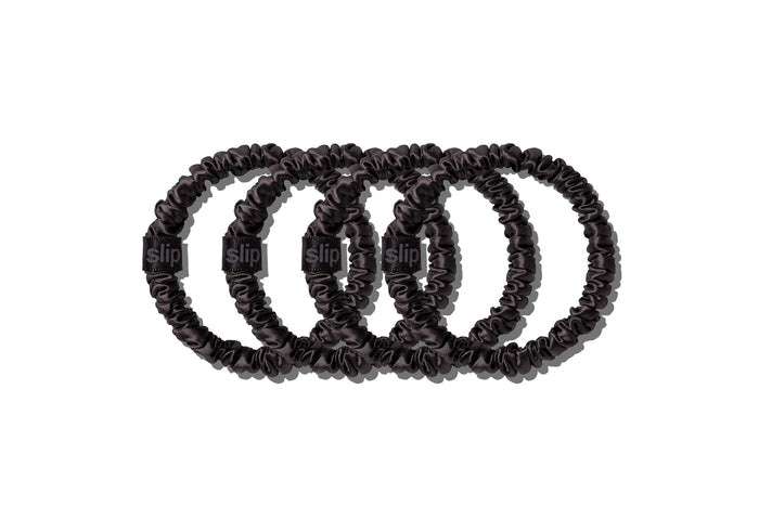 A set of four slip silk black skinny scrunchies on a white background.