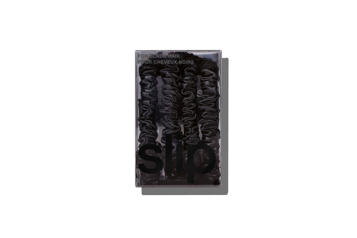 A set of four slip silk black skinny scrunchies in branded packaging on a white background.