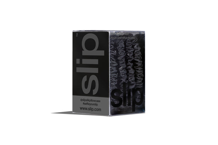 A set of four slip silk black skinny scrunchies in branded packaging on a white background.