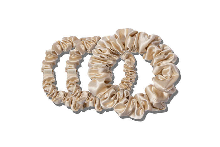 A set of three blonde slipsilk scrunchies, including two midi and one large, on a white background.