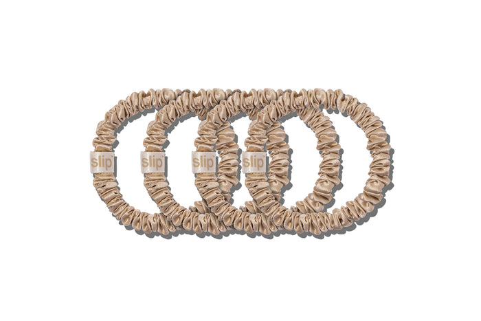 A set of four slip silk blonde skinny scrunchies on a white background.