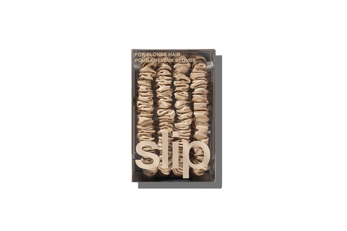 A set of four slip silk blonde skinny scrunchies in branded packaging on a white background.
