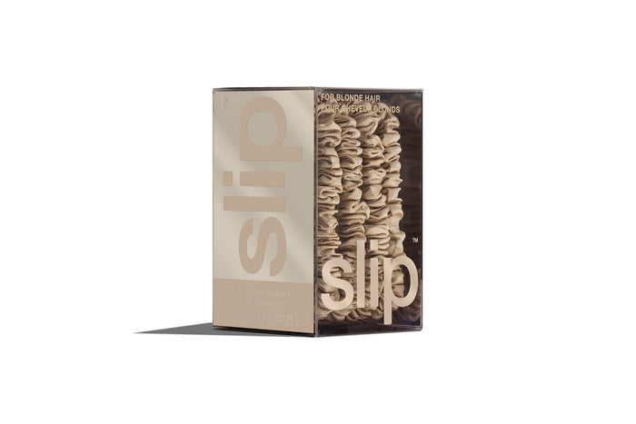 A set of four slip silk blonde skinny scrunchies in branded packaging on a white background.