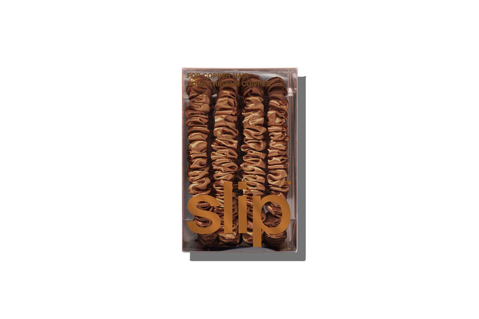 A set of four slip silk copper skinny scrunchies in branded packaging on a white background.
