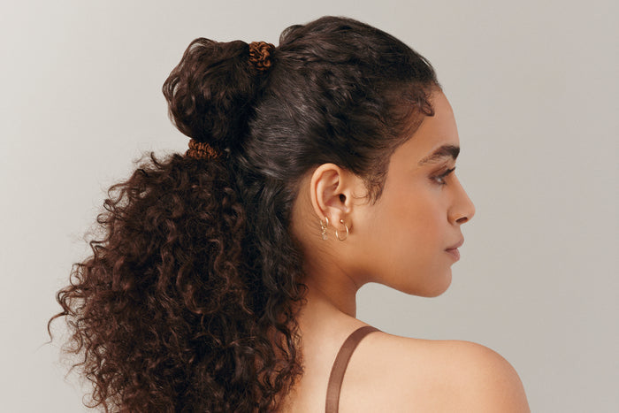 A woman wearing a dark brown slip silk skinny scrunchie in her hair.