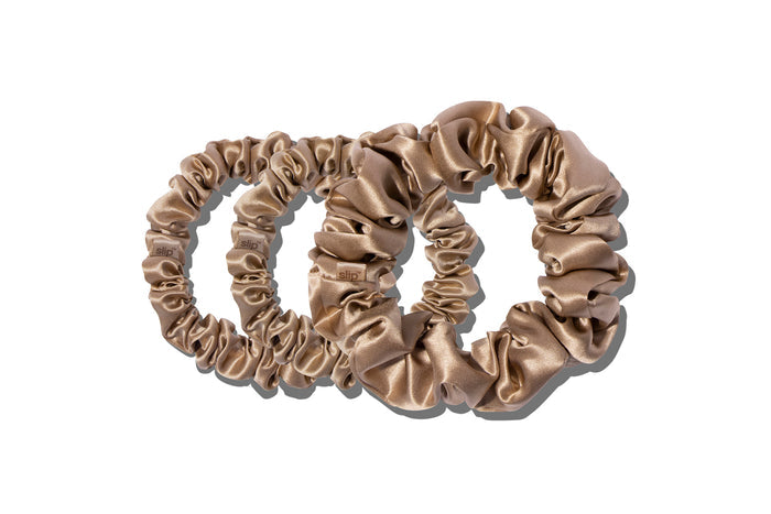 A set of three light brown slipsilk scrunchies, including two midi and one large, on a white background.