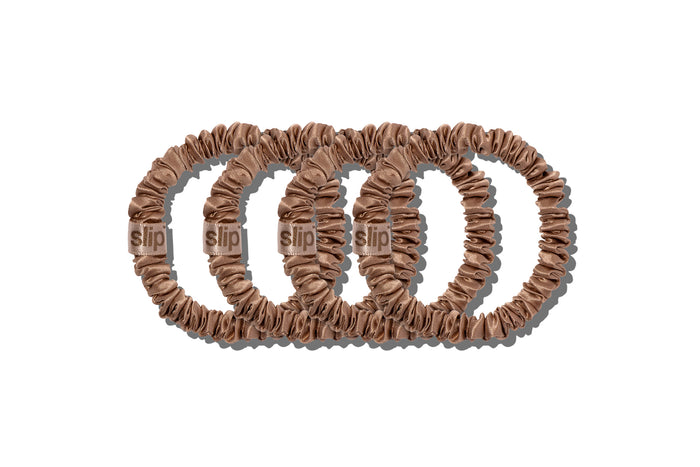 A set of four slip silk light brown skinny scrunchies on a white background.