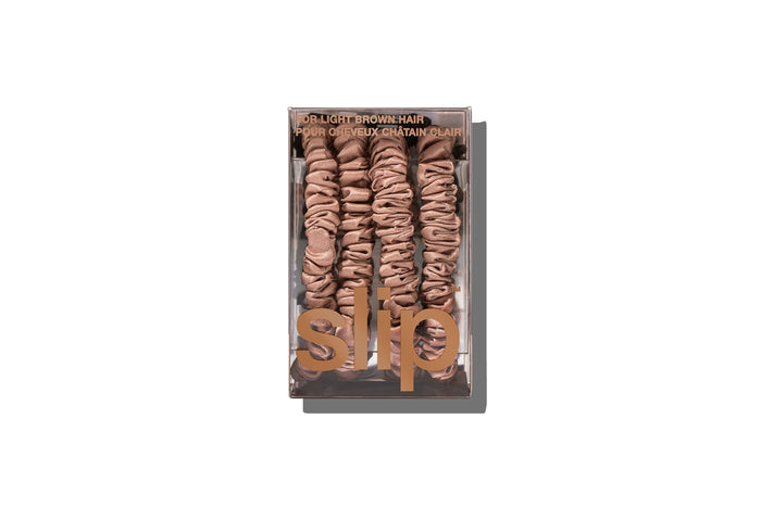 A set of four slip silk light brown skinny scrunchies in branded packaging on a white background.