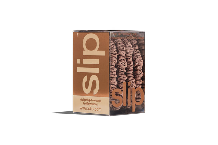 A set of four slip silk light brown skinny scrunchies in branded packaging on a white background.