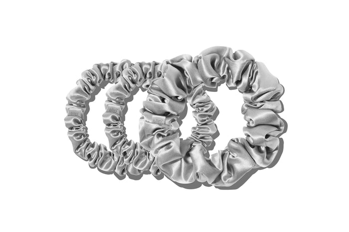A set of three silver slipsilk scrunchies, including two midi and one large, on a white background.