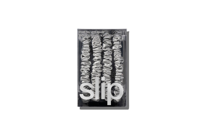 A set of four silver slip silk skinny scrunchies in branded packaging on a white background.