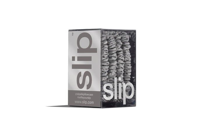 A set of four silver slip silk skinny scrunchies in branded packaging on a white background.