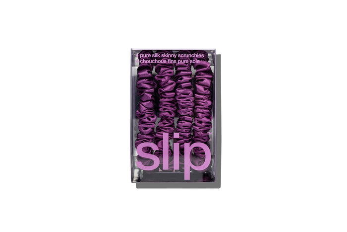 Set of purple silk skinny scrunchies in slip packaging on a white background