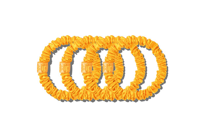 Set of four yellow slip skinny silk scrunchies on a white background