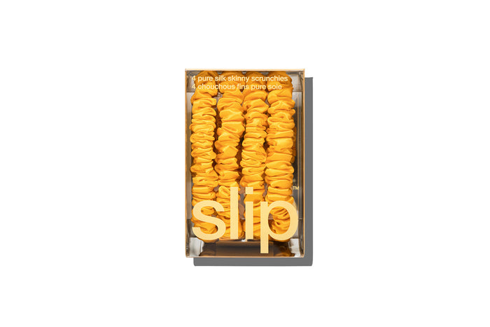 Set of yellow silk skinny scrunchies in slip packaging on a white background