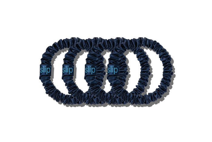 Set of four navy silk skinny scrunchies on a white background