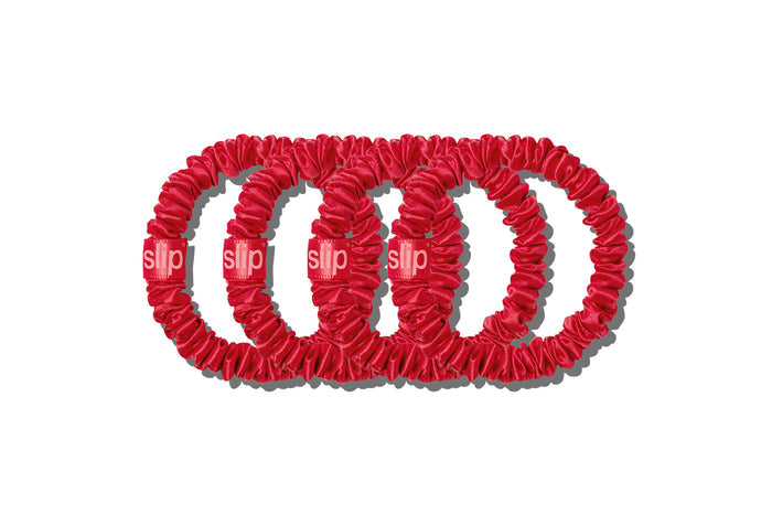 Set of four red slip skinny silk scrunchies on a white background