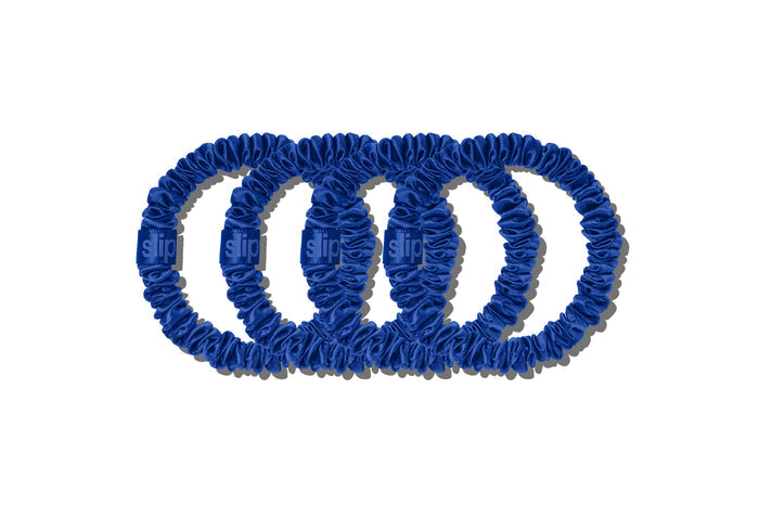 Four blue silk hair scrunchies on a white background