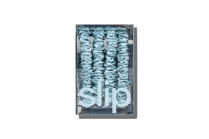 Sky blue silk skinny scrunchies in slip packaging on a white background