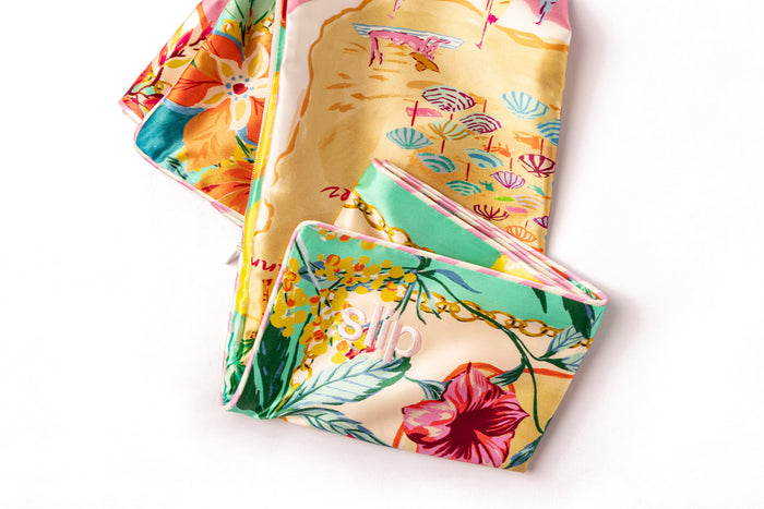 A colorful slip silk pillowcase with a beach map graphic print folded on white background.