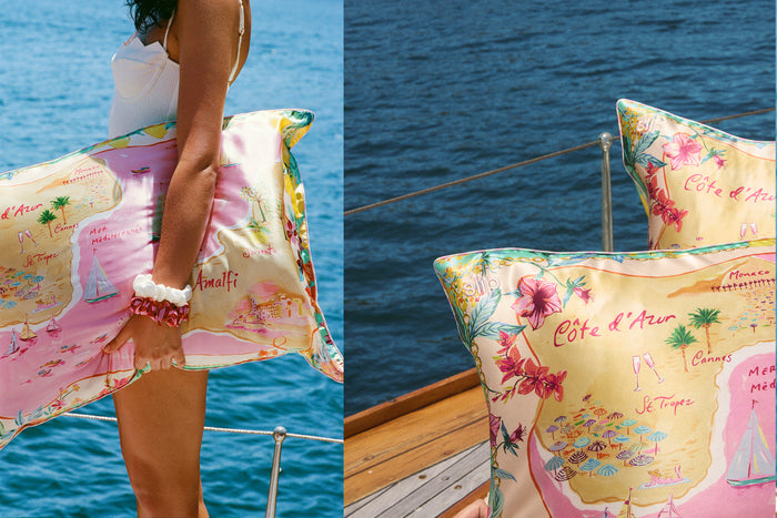 Woman holding slip silk pillowcase with colourful map graphic on a boat. Stacked slip silk pillowcase with colourful map graphic on a boat.