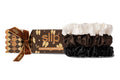 Three slip large silk scrunchies in white, chocolate, and black are displayed next to their branded packaging cracker box on a clean white background. The box is brown with gold patterns and a brown velvet bow.