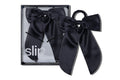 Black silk hair bow and scrunchie set with slip packaging on a white background.