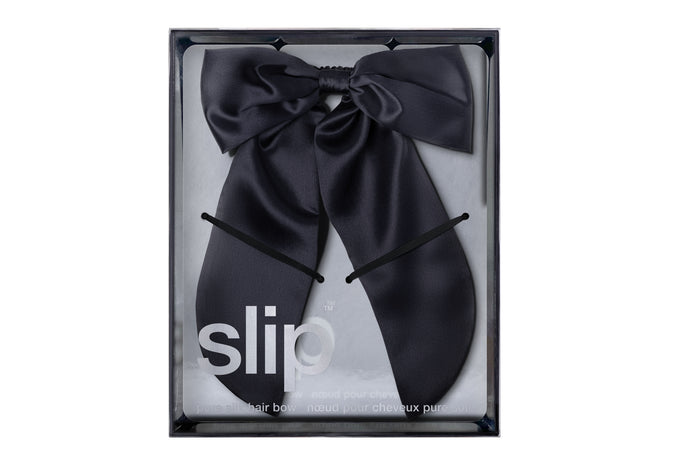 Black silk hair bow in a clear box with slip branding on a white background.