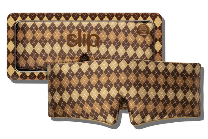 A slip blockout sleep mask with a brown, tan, and beige argyle pattern, shown in front of its matching patterned packaging box on a white background.