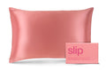 A blush pink queen-sized pillowcase with a zipper, displayed alongside its packaging box with the brand 'slip' visible.