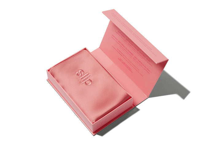 Blush pink silk pillowcase in slip packaging on a white background.