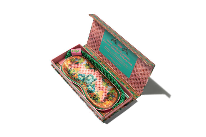 A floral patterned slip silk sleep mask with Capricorn star sign details. Displayed in a matching branded open packaging box.