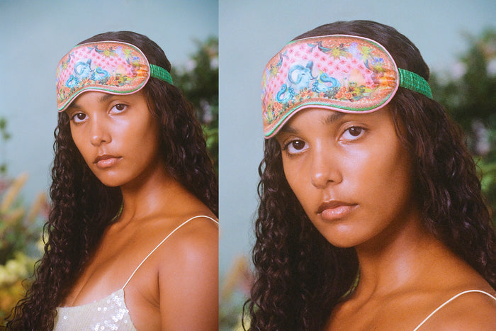 A woman wearing a floral patterned slip silk sleep mask with Capricorn star sign details.