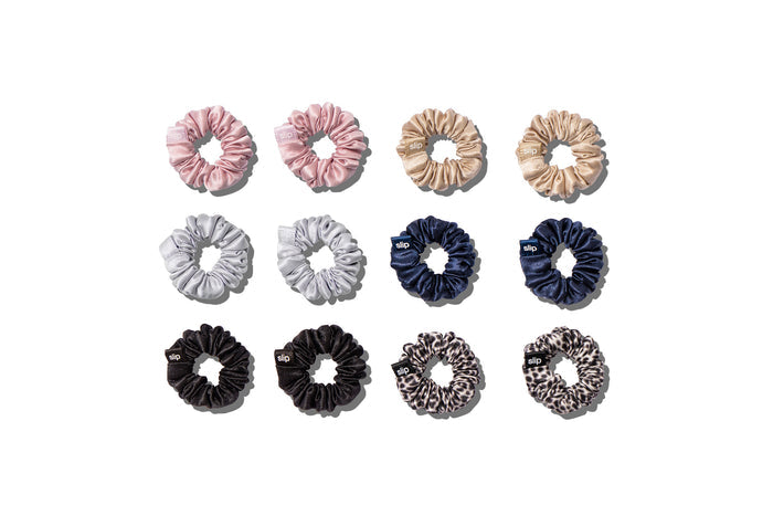 A set of twelve Slip silk minnie scrunchies in various colors including pink, caramel, silver, navy, leopard, and black on a white background.