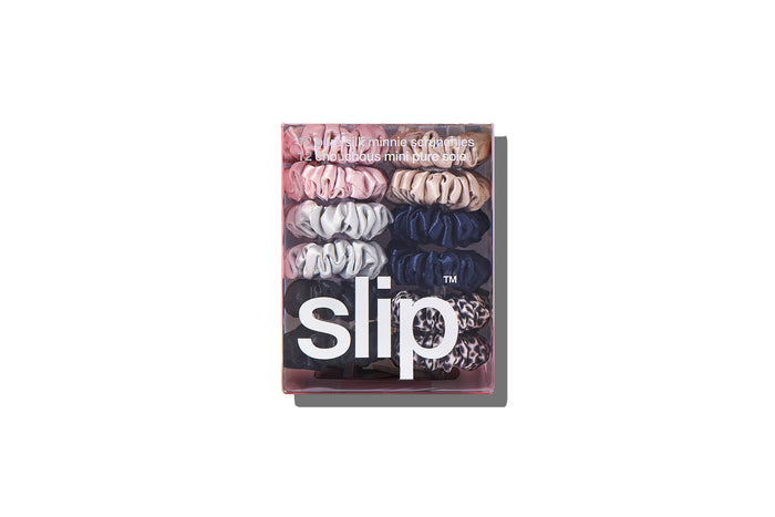 A set of twelve Slip silk minnie scrunchies in various colors including pink, caramel, silver, navy, leopard, and black in branded packaging on a white background.