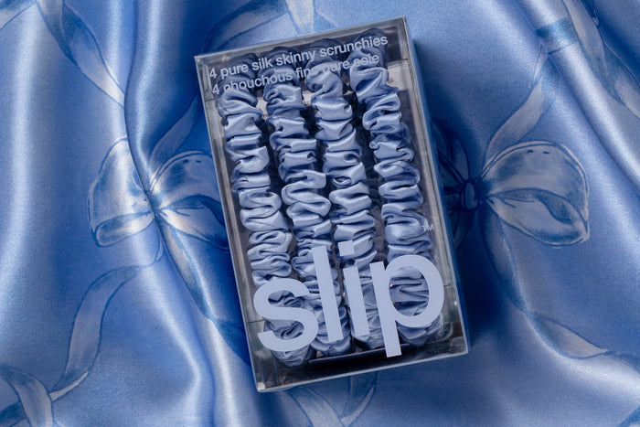 Box of 'slip' cornflower blue silk scrunchies on a blue silk background.