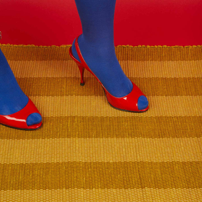 Red high-heeled shoes with blue toes Essential Floor Mat in Mustard with red background.