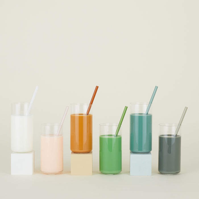 Row of drinking glasses filled with various colorful liquids, each with an Essential Glass Straw.