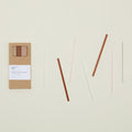 Kraft colored gift box of Essential Glass Straws in Warms, with straws scattered nearby.