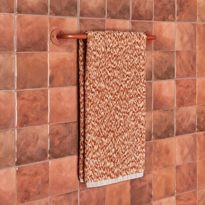 Essential towel bar in Terracotta with Space Dye terry hand towel in Terracotta on tiled wall.