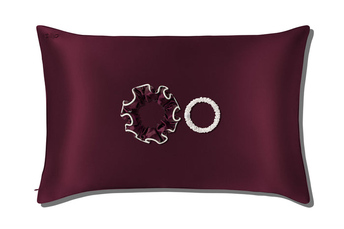 A slip silk queen pillowcase in crimson with two slip silk scrunchies displayed against a clean white background.