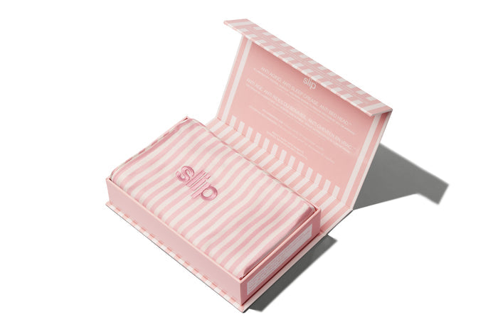 A white and pink stripe slip silk queen pillowcase in open branded packaging on a white background.