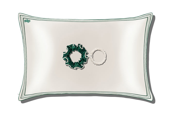 A white silk pillowcase, a green silk large scrunchie and a skinny white silk scrunchie on a white background