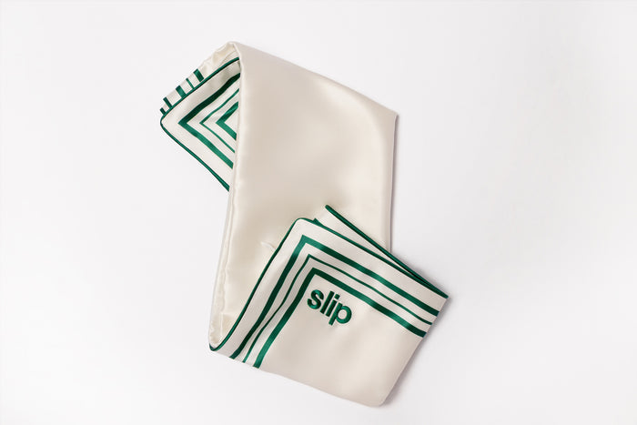 White pillowcase with green patterns and 'slip' embroidery on a white background