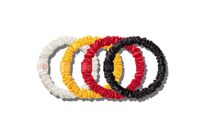 Set of four hair scrunchies in white, marigold, red, and black on a white background