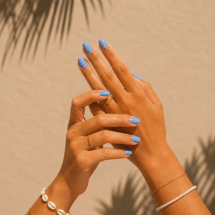 Good Vibes Only sky blue gel nail stickers by Maniac Nails, hands raised against palm shadow