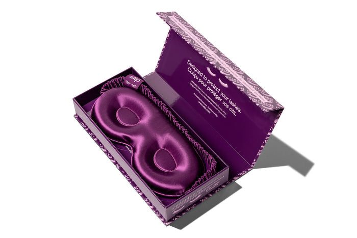 A dark purple slip silk contour sleep mask , designed for eyelash extension wearers. Displayed in open branded packaging on a white background.